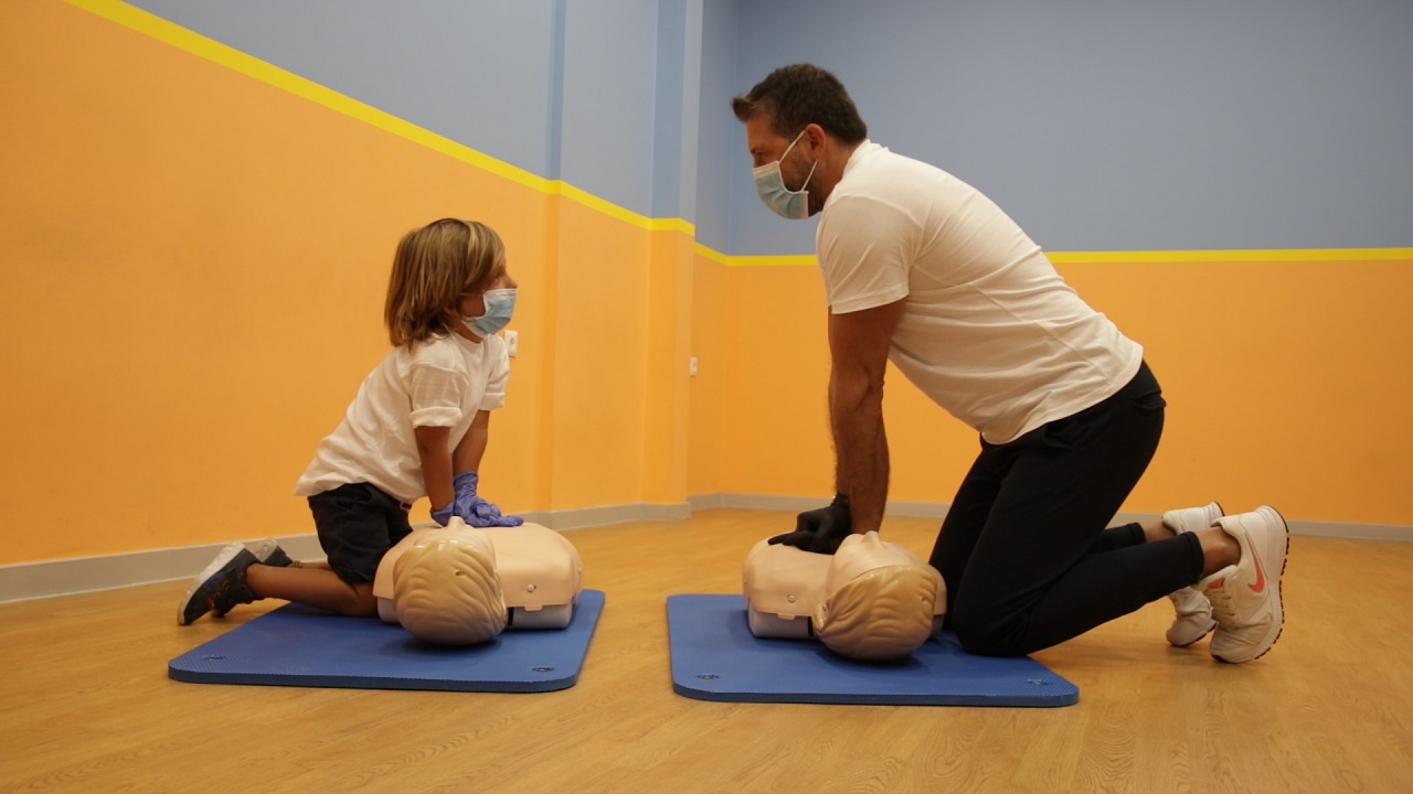 cpr Παιδί εκπαιδεύεται στην ΚΑΡΠΑ με ενήλικα εκπαιδευτή και ομοίωμα ανθρώπινου θώρακα